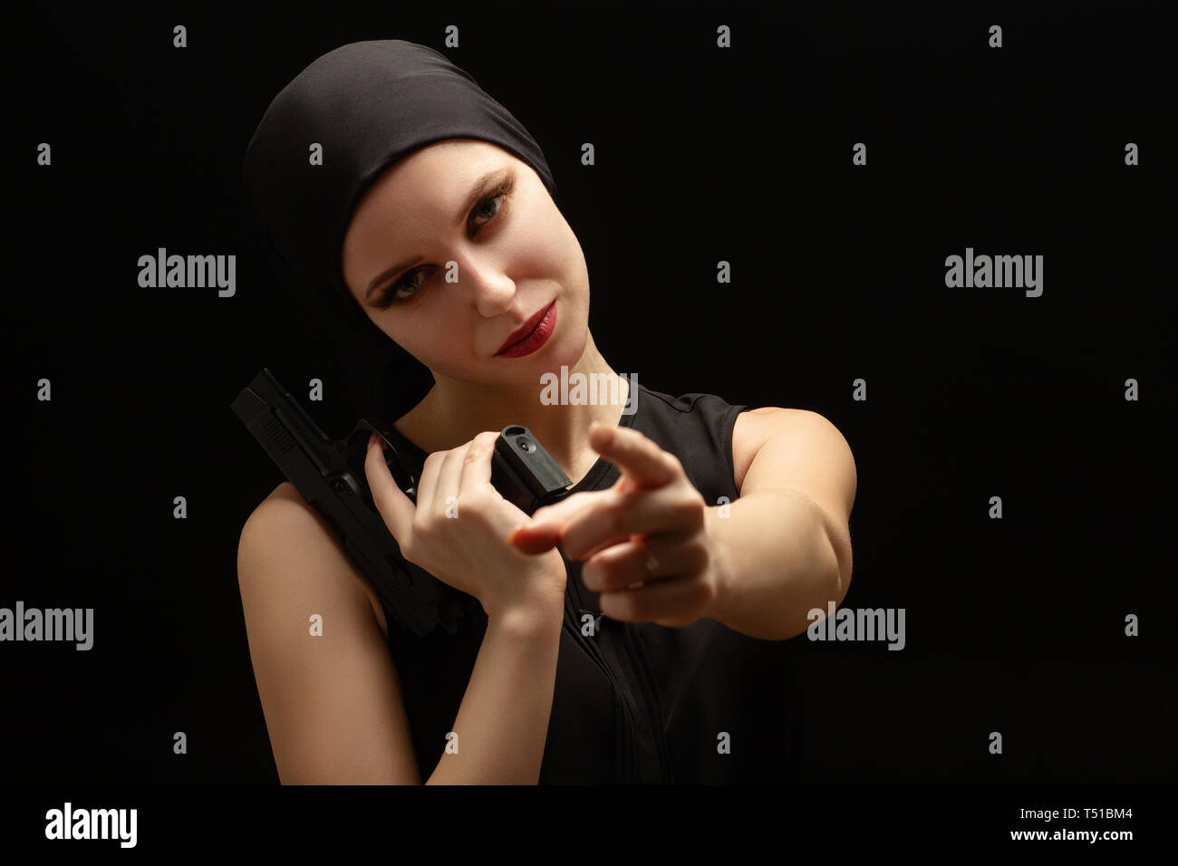 serious girl with gun point at camera on black background Stock Photo