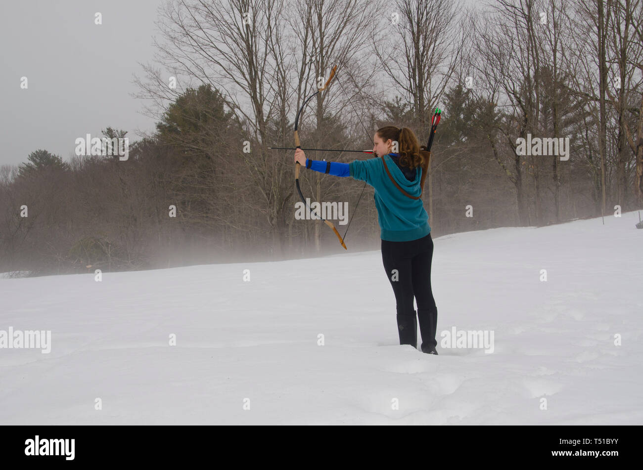 Woman shooting archery in snow, Maine, USA Stock Photo