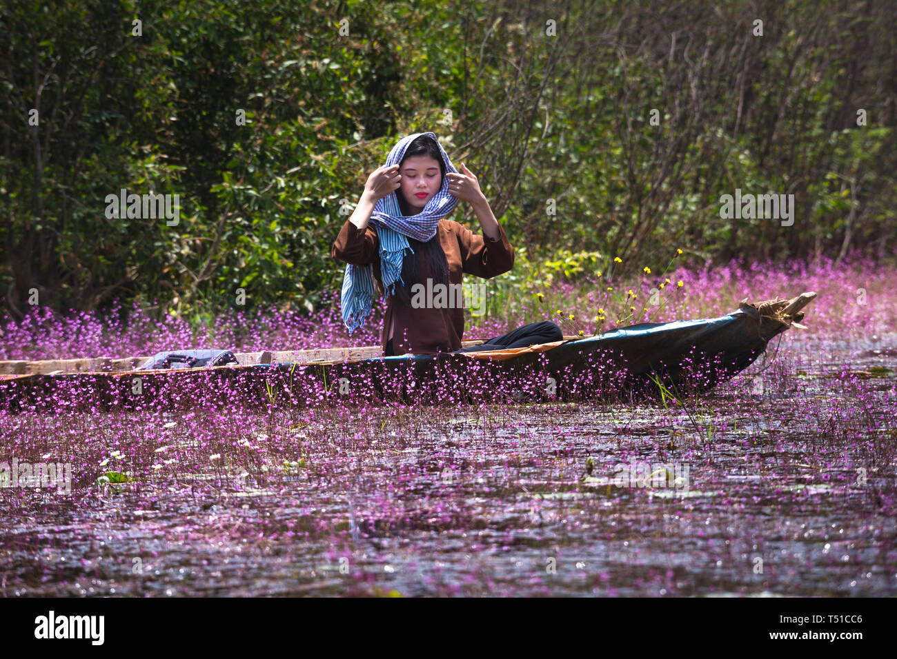Tram Chim Nature Reserve, Dong Thap Province, Vietnam - March 18, 2017 : Image of a farmer happy couple are boating on a canal full of pink ultricular Stock Photo