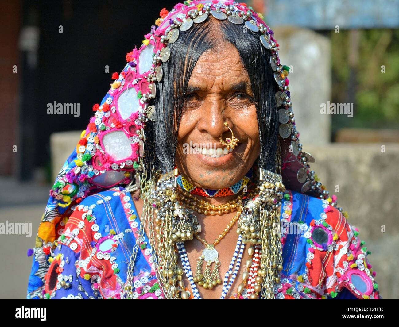 Elderly Indian Lambani tribal woman from Karnataka (Banjara woman, Indian gypsy) with traditional chin tattoos and nose jewelry smiles for the camera. Stock Photo