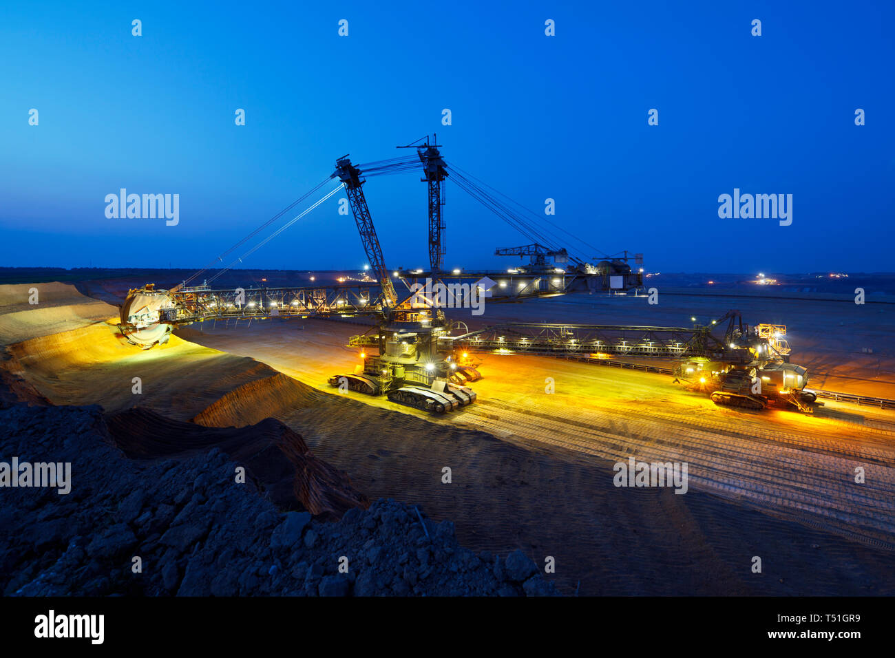 A lignite pit mine with a giant bucket-wheel excavator, one of the worlds largest moving land vehicles with night blue sky. Stock Photo