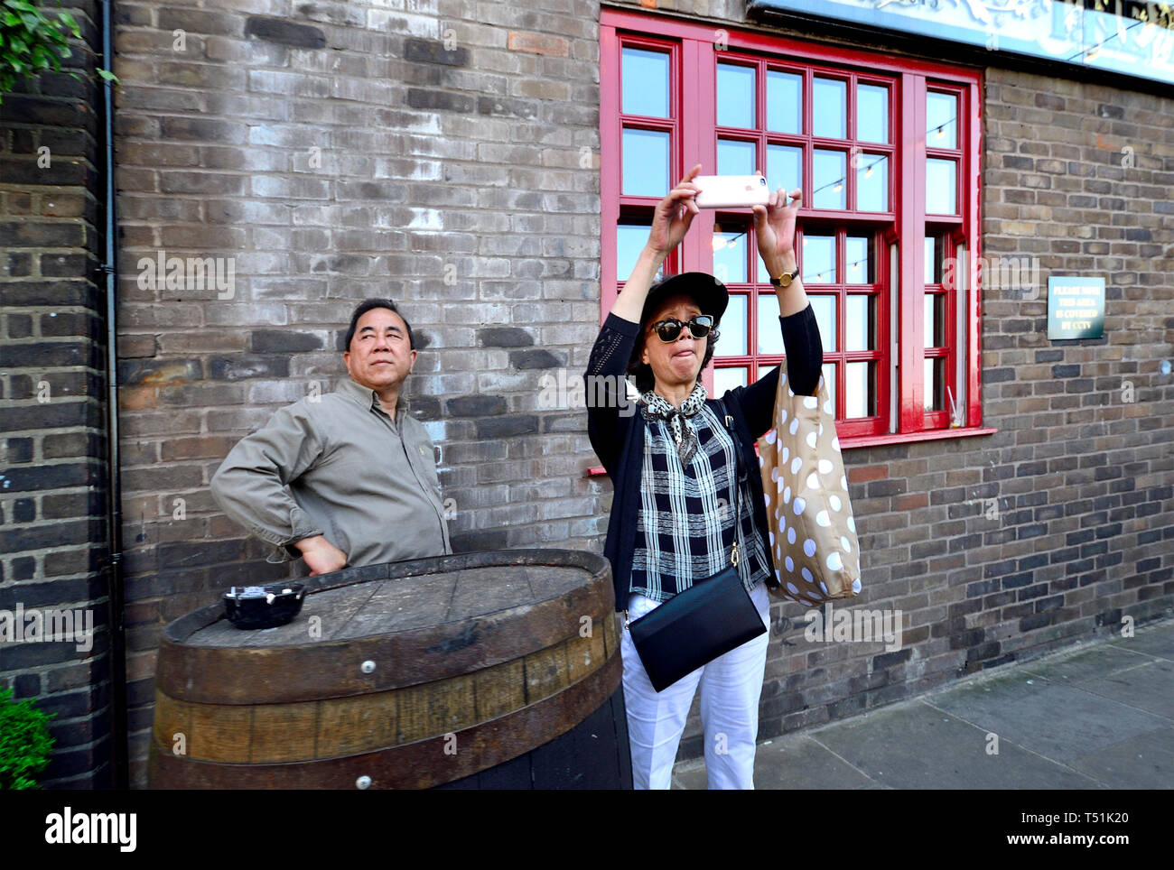 London, England, UK. Japanese woman taking a photo in Southwark Stock Photo