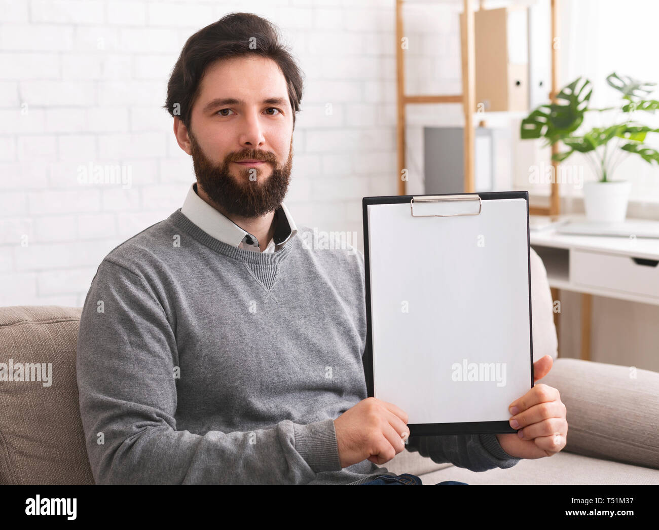 Confident psychotherapist showing white blank clipboard at camera Stock Photo