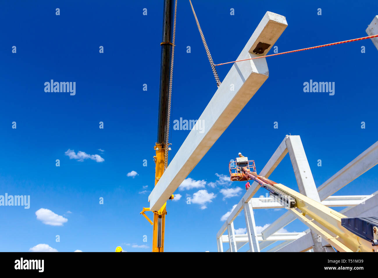 Worker is helping mobile crane to manage concrete joist for assembly ...