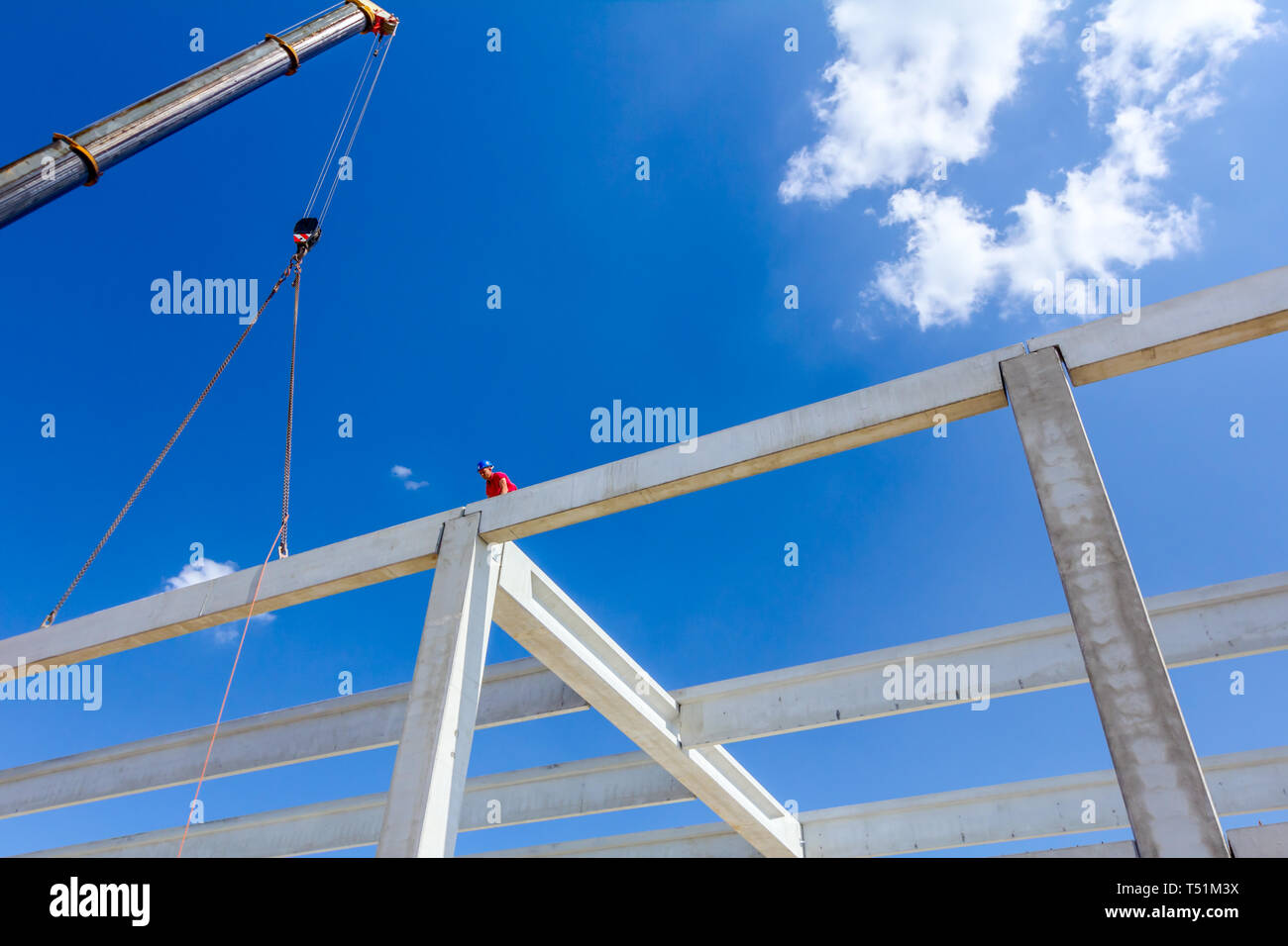 Worker is helping mobile crane to manage concrete joist for assembly ...