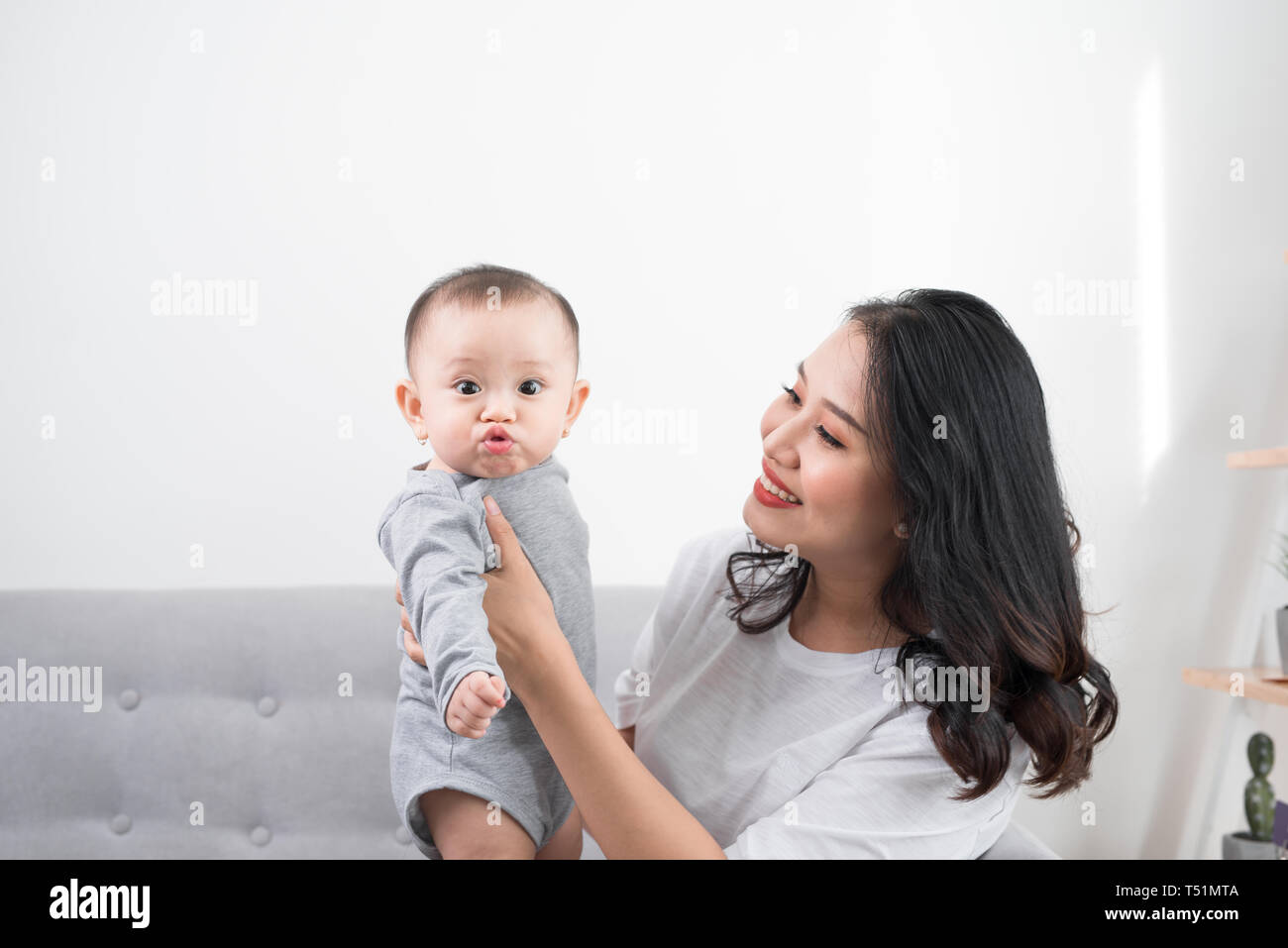 Young mother with her one years old little son dressed in pajamas are relaxing and playing in the living room at the weekend together, lazy morning, w Stock Photo