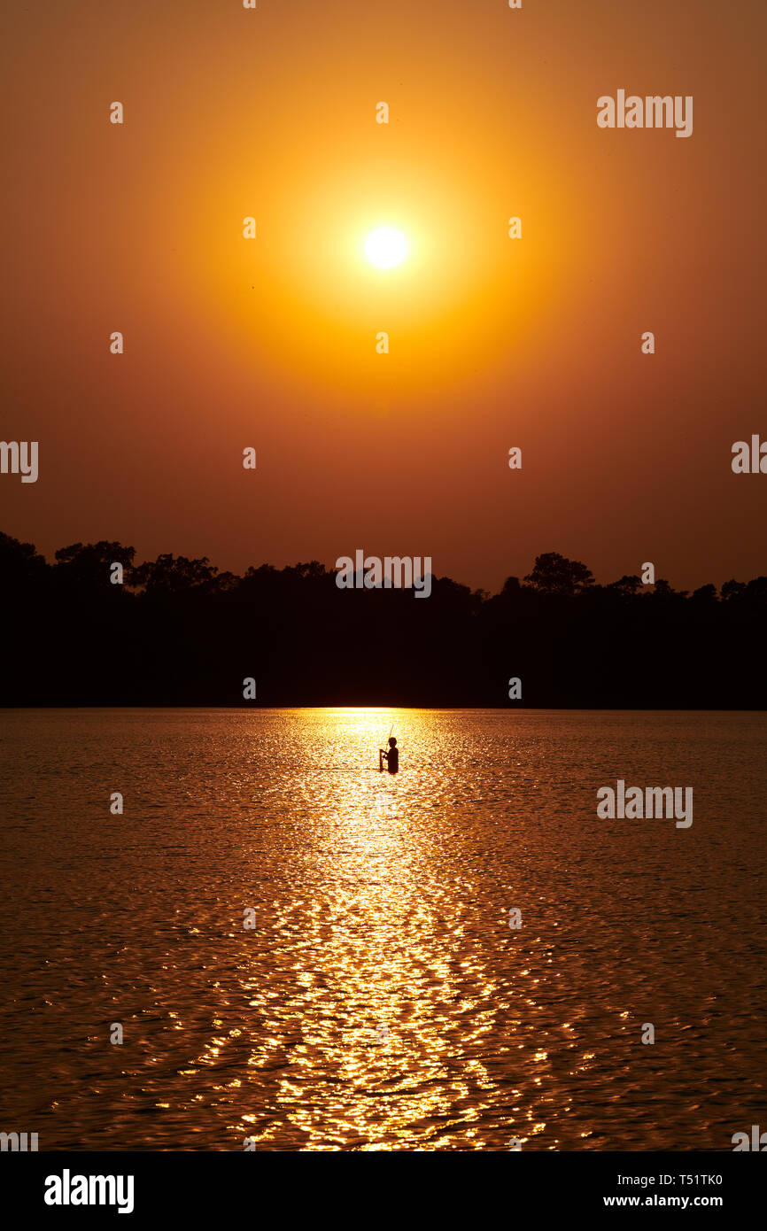 Sunset over Srah Srang with a fisherman in the lake Stock Photo