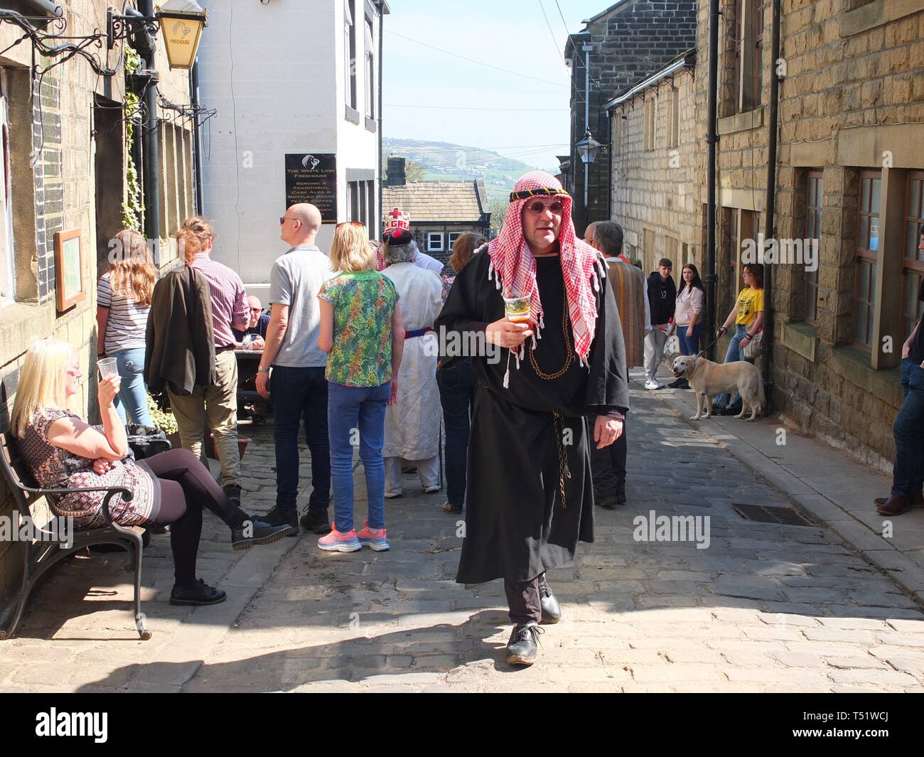 As spectators throng streets outside the village pubs one of performers in the Good Friday Heptonstall Pace Egg Play makes his way to Weavers Square Stock Photo