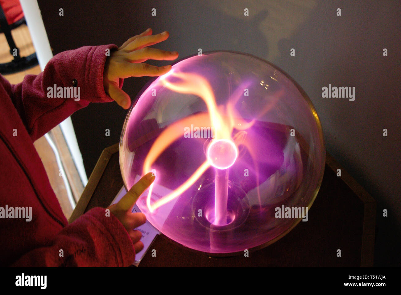Scientific experiment for kids. Hands on a purple plasma ball. Stock Photo