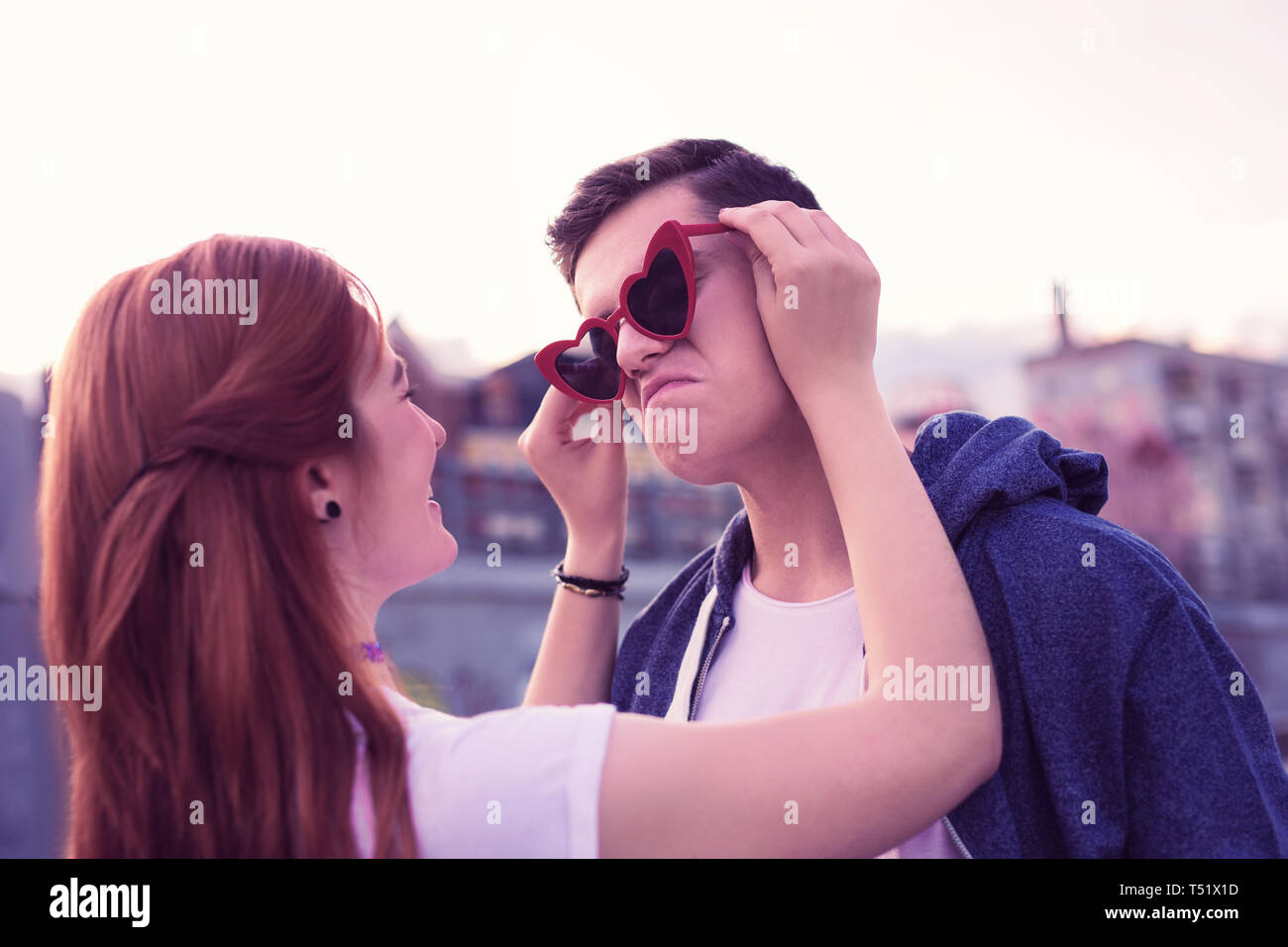 Laughing ginger girl attaching funky red sunglasses to the face of her