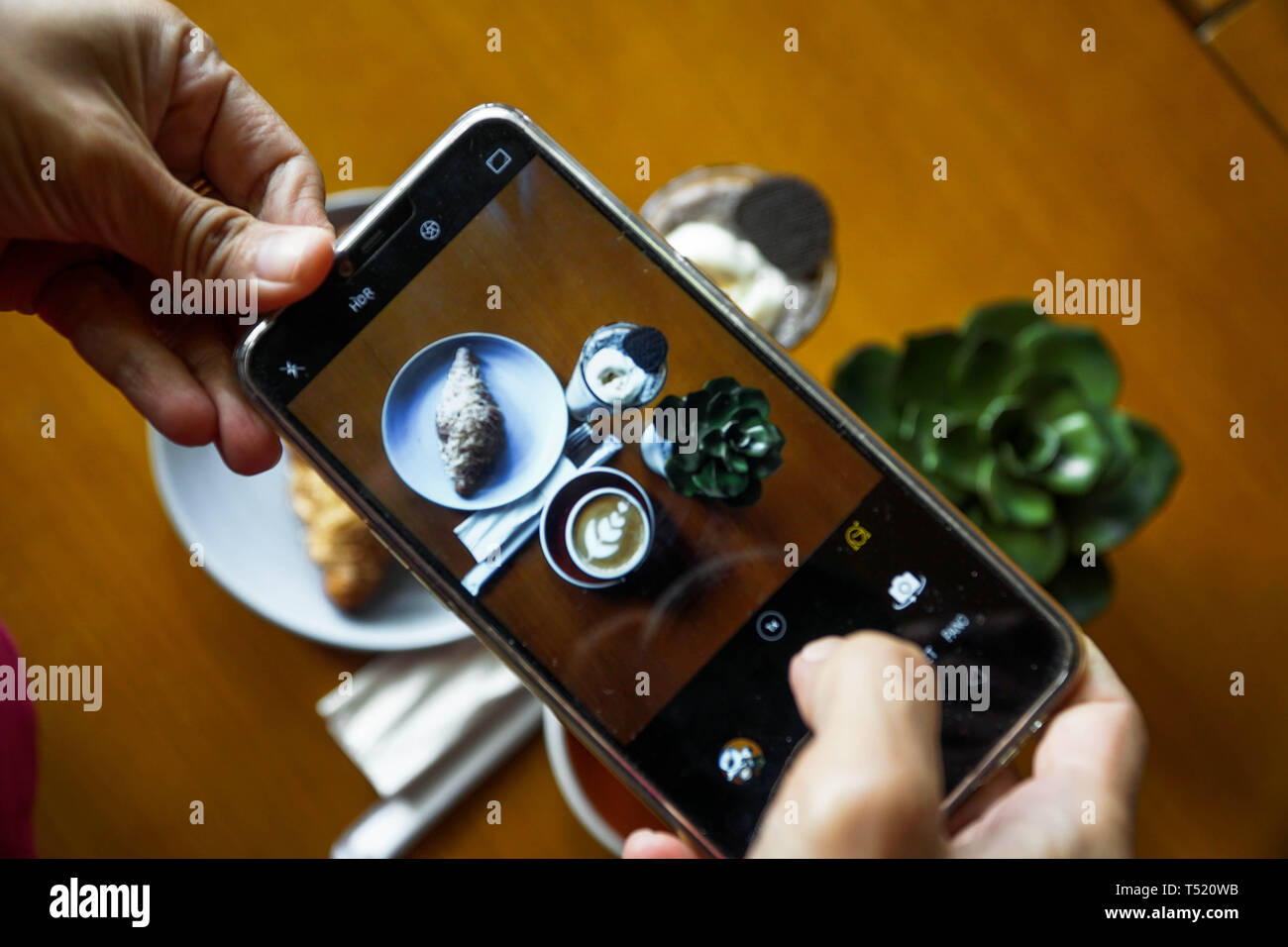 Food photography using mobile phone. Product photos of coffee latte, croissant chocolate, and blue ocean. Top view photo of food at a cafe to be Stock Photo