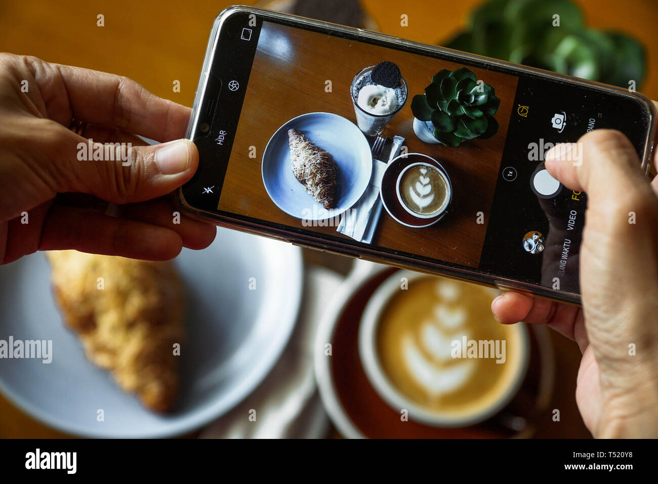 Food photography using mobile phone. Product photos of coffee latte, croissant chocolate, and blue ocean. Top view photo of food at a cafe to be Stock Photo
