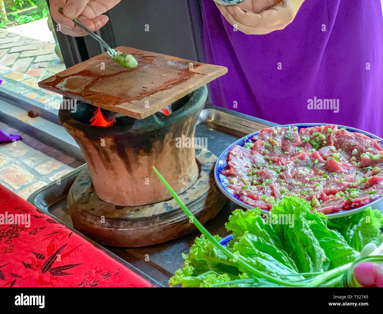 Woman cooking regional speciality Hue style beef on table side hibachi