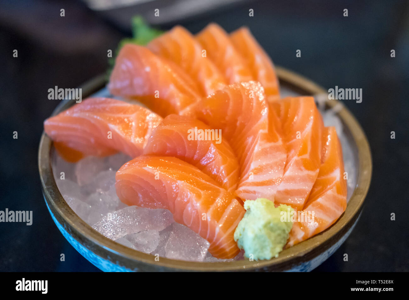 Salmon sashimi with vegetable and ice in a bowl, served in a restaurant ...