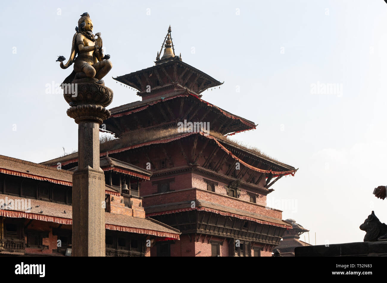 Beautiful sculpture of Garuda on a stone pillar, in the foreground of Krishna Mandir at Patan Durbar Square. Stock Photo