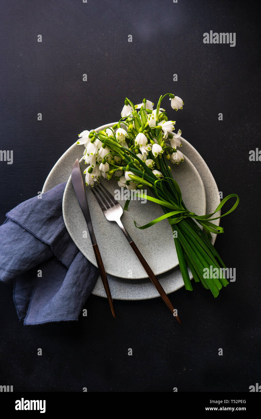 Feastive table setting for holiday Easter dinner decorated with spring snowdrop flowers on rustic table with copy space Stock Photo