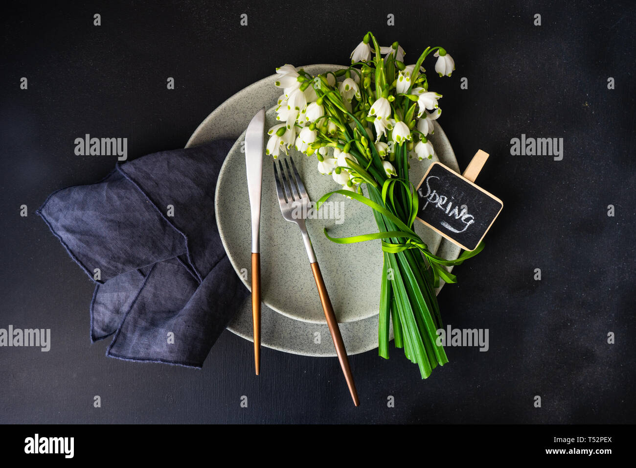 Feastive table setting for holiday Easter dinner decorated with spring snowdrop flowers on rustic table with copy space Stock Photo