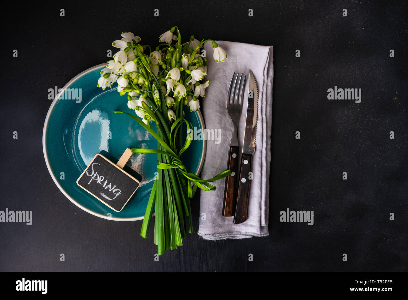 Feastive table setting for holiday Easter dinner decorated with spring snowdrop flowers on rustic table with copy space Stock Photo