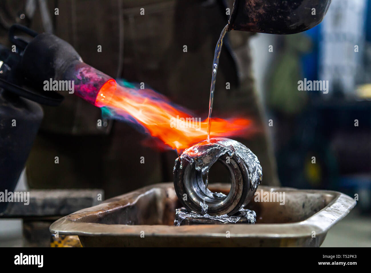 Professional male worker using a gas torch to melt lead metal. Closeup