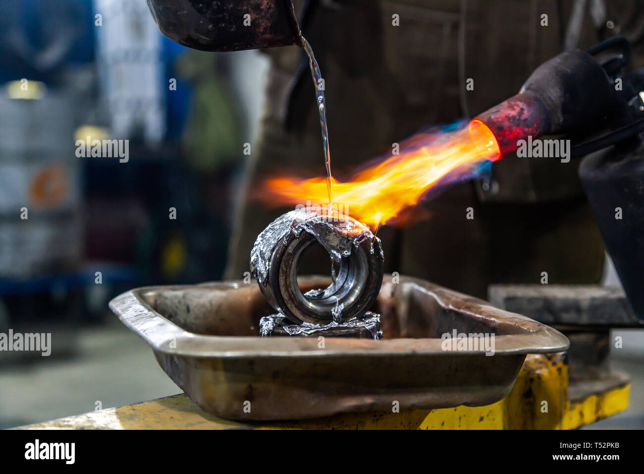 Professional male worker using a gas torch to melt lead metal. Closeup