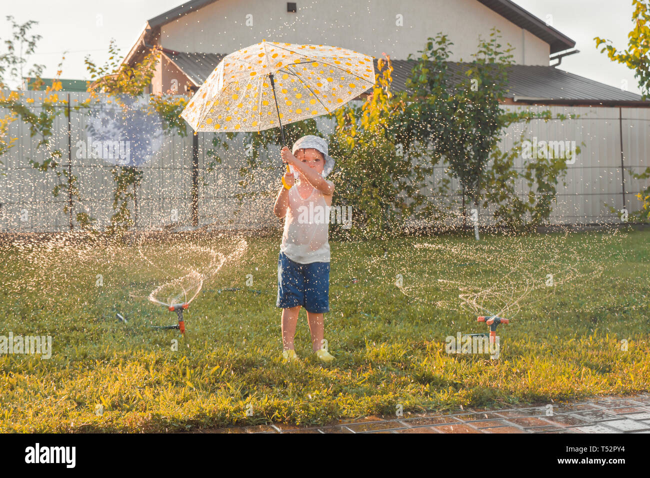 Summer activities. Children playing outdoor. Happy boy playing outdoor with watering system. Summer vacation. Summer holidays with children. Happy kid Stock Photo