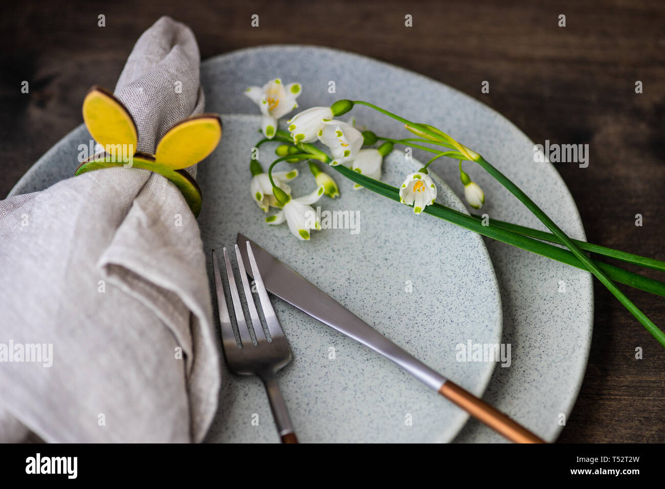 Feastive table setting for holiday Easter dinner decorated with spring snowdrop flowers on rustic table with copy space Stock Photo