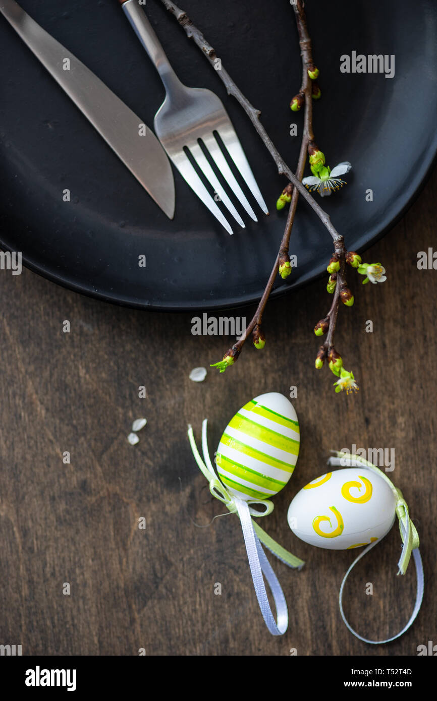 Feastive table setting for holiday Easter dinner decorated with blooming cherry flowers on rustic table with copy space Stock Photo