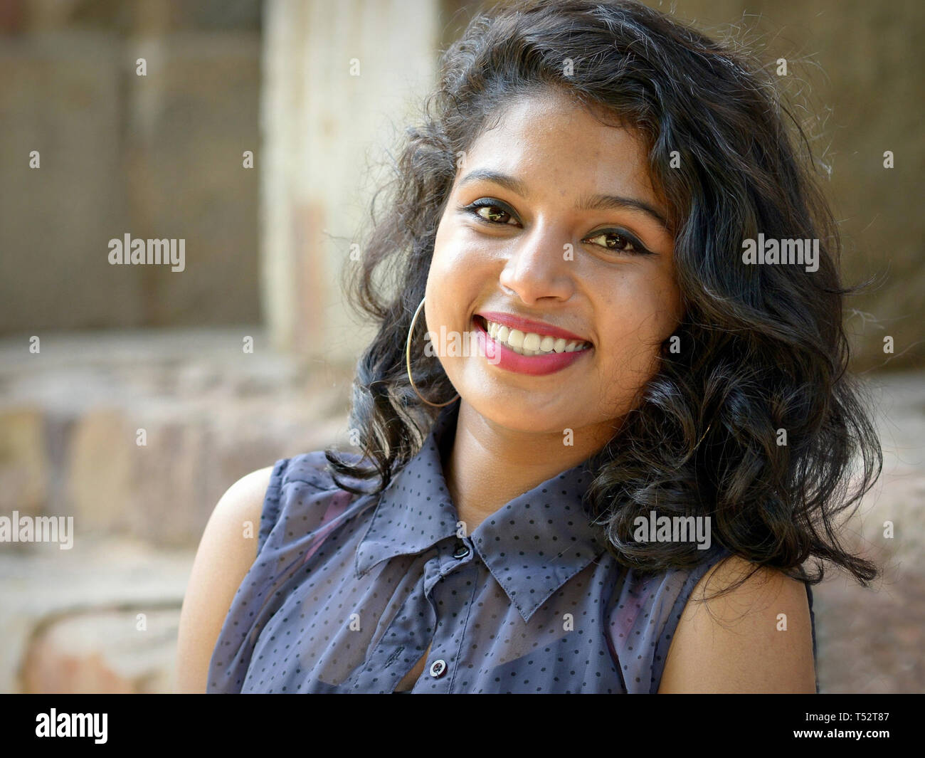 Attractive young Indian woman with hoop earrings and beautiful hair poses for the camera at New Delhi’s tranquil Lodhi Gardens. Stock Photo