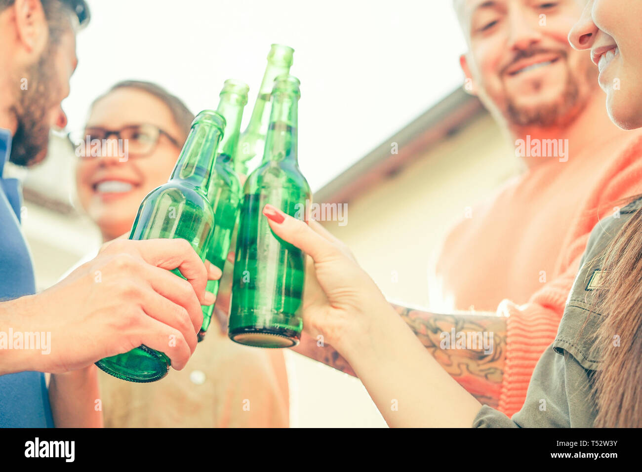 Happy friends toasting beers outdoor - Young people having fun cheering and drinking alcohol at rooftop - Friendship, youth, lifestyle concept Stock Photo