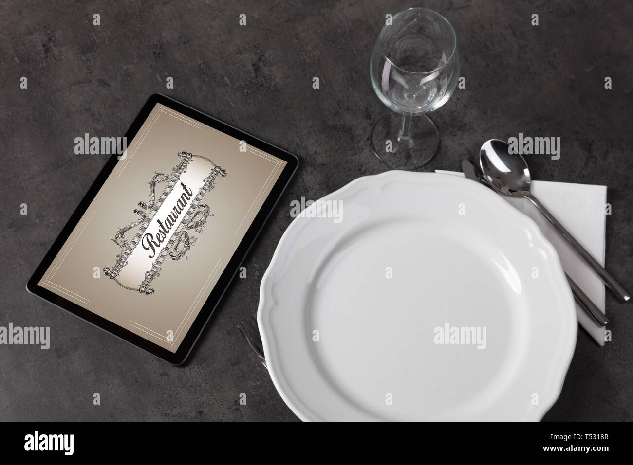 Tablet with stylish restaurant logo and laid table  Stock Photo