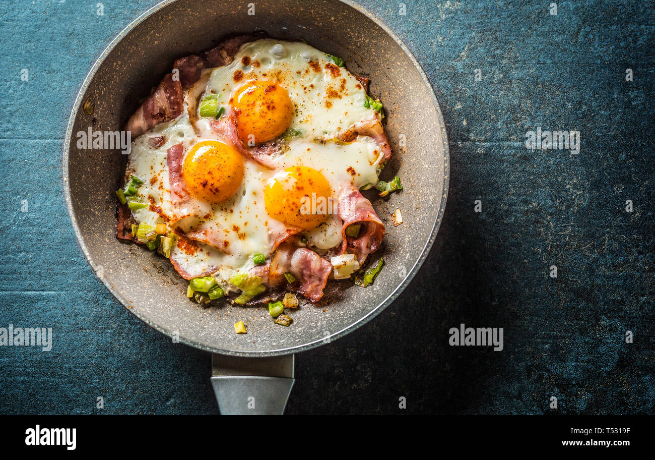 English breakfast fried bacon ham and eggs in ceramic pan Stock Photo