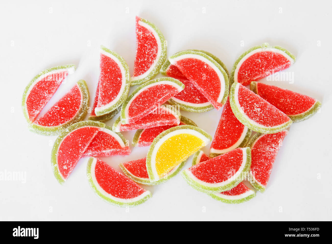 Sweet sugar marmalade in the form of slices of watermelon and lime lies on the white surface of the store counter. Stand out from the crowd. Dessert. Stock Photo