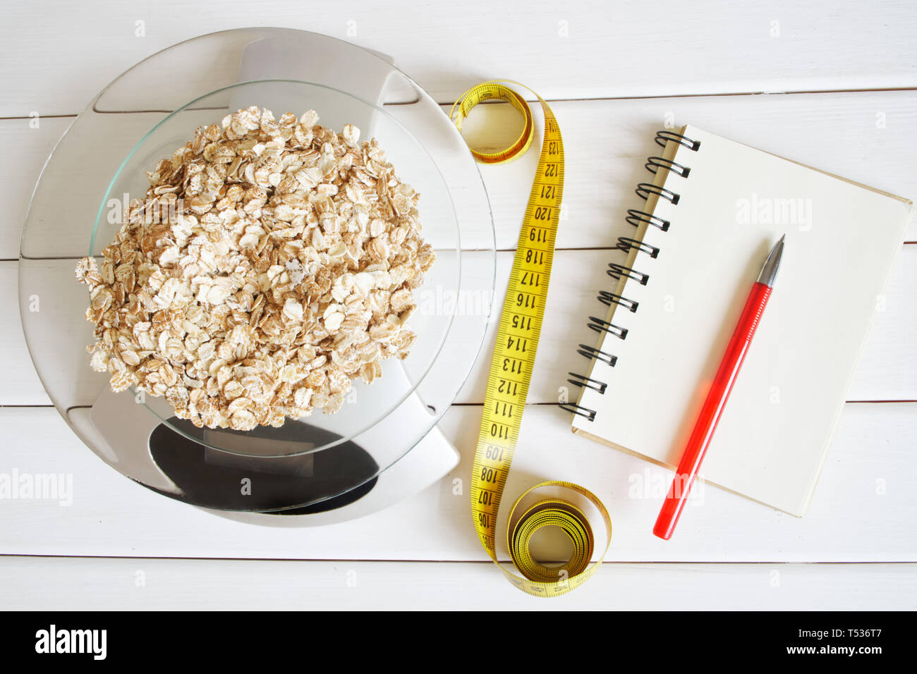 Counting and recording the amount of carbohydrates, proteins, calories and fats in food. Flakes from four cereals on kitchen scales. Oatmeal, wheat, b Stock Photo