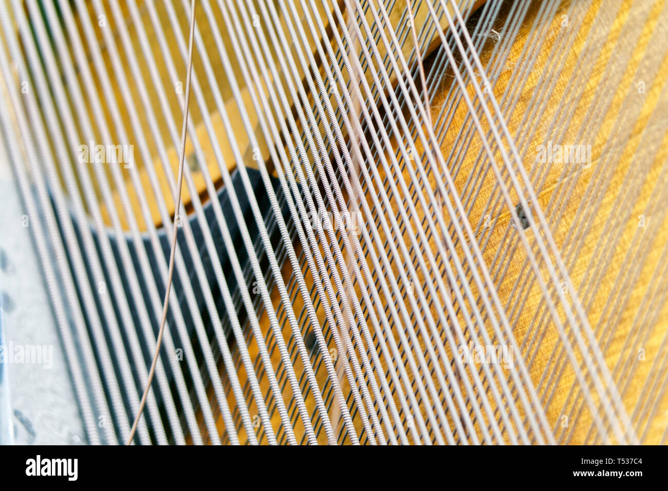 Strings inside the mechanism of the old piano. Sound technology. Shallow depth of field. The mechanism of musical instruments. Closeup. Stock Photo