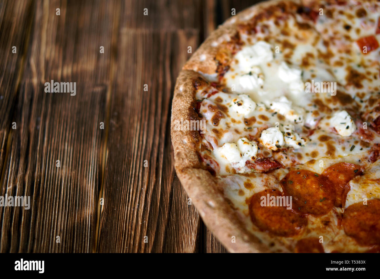 Composite-assorted pizza on a natural wooden surface of pine boards. Daylight. Close-up. Free space to sign. Shallow depth of field. Stock Photo
