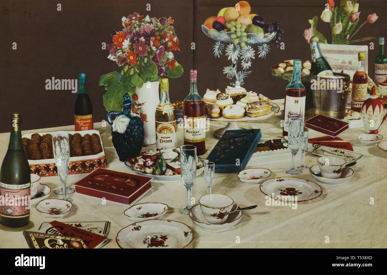 Dinner table served for typical Soviet family full of tasty deserts and alcoholic drinks depicted in the colour illustration in the Book of Tasty and Healthy Food published in the Soviet Union (1953). Bottles of Armenian brandy Yerevan Cognac and Georgian and Armenian wine are seen in the picture. Stock Photo