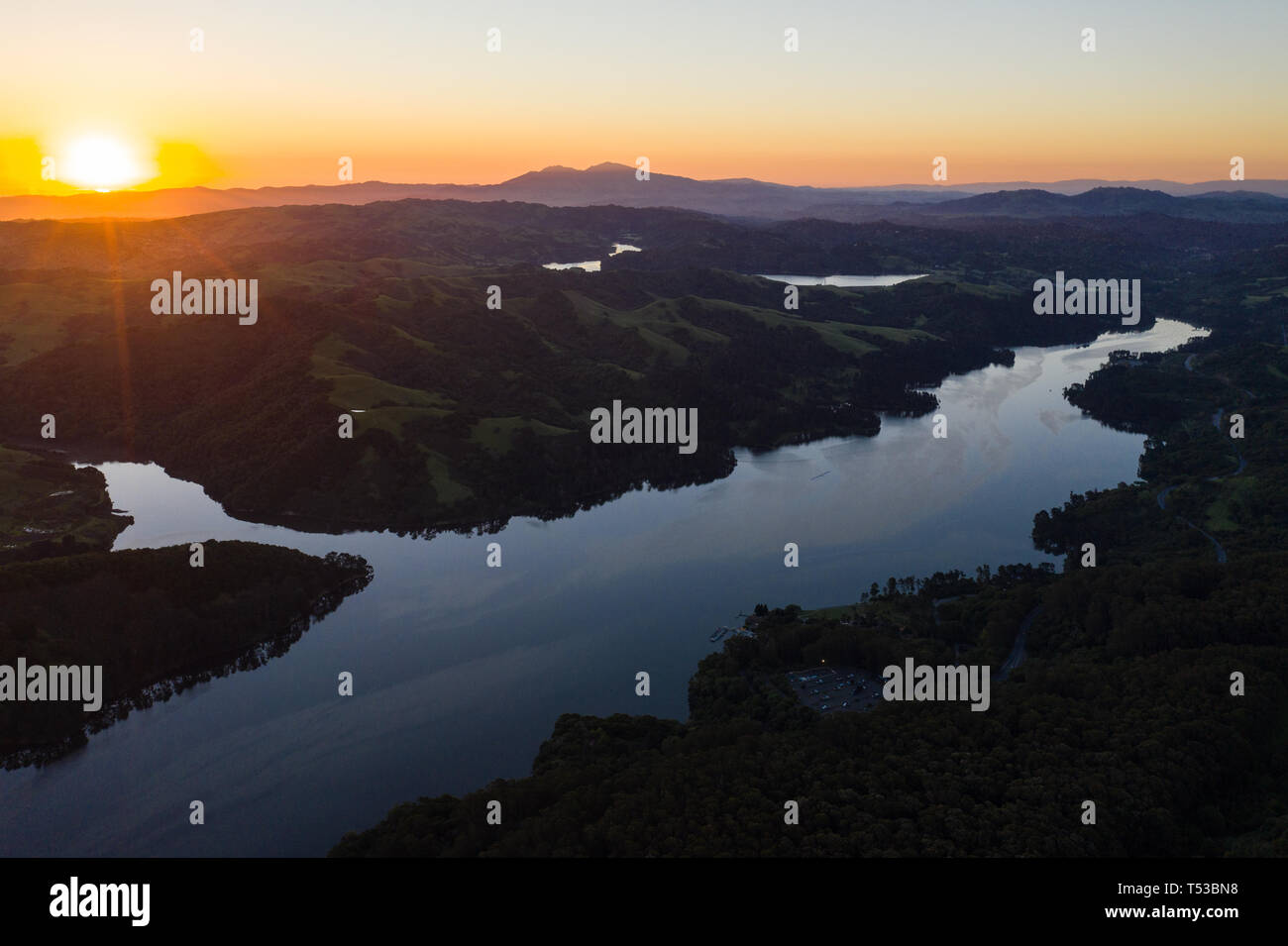 A beautiful dawn breaks over the green hills around the San Pablo Reservoir in Northern California. A wet winter has caused lush vegetation growth. Stock Photo
