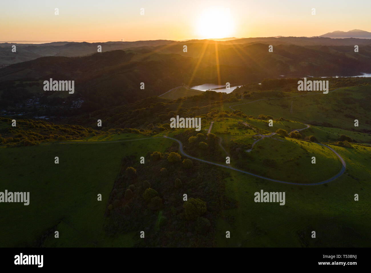 A beautiful dawn breaks over the green hills around the San Pablo Reservoir in Northern California. A wet winter has caused lush vegetation growth. Stock Photo