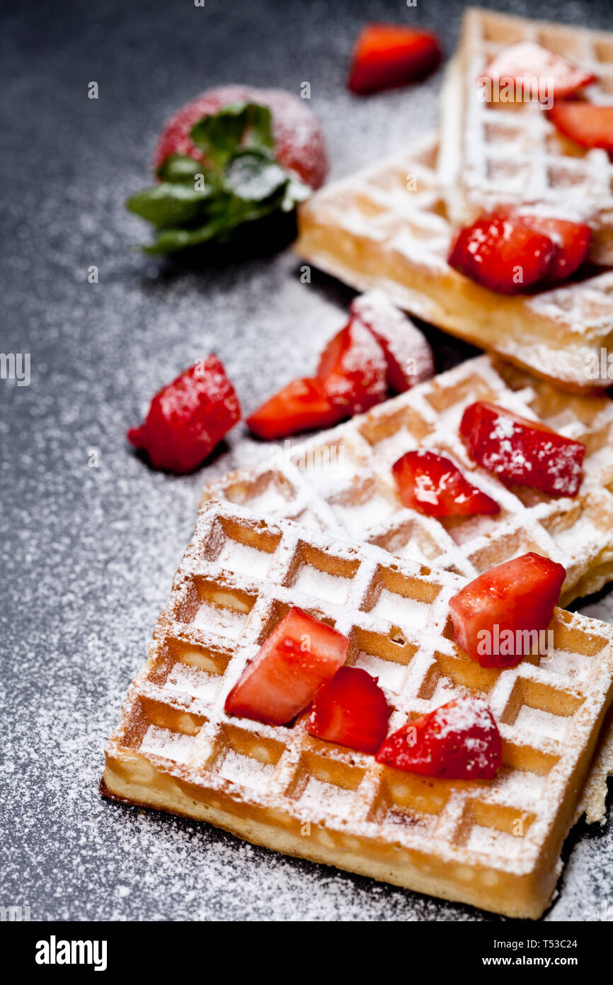 Belgium waffers with strawberries and sugar powder on black board ...