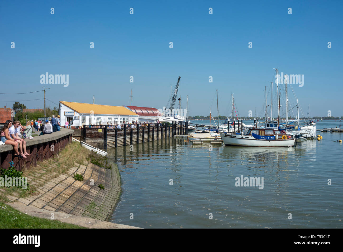 The Lock Tea room at Heybridge Basin, Essex, UK on a bright sunny day with people. River Blackwater with boats. People eating outside enjoying weather Stock Photo