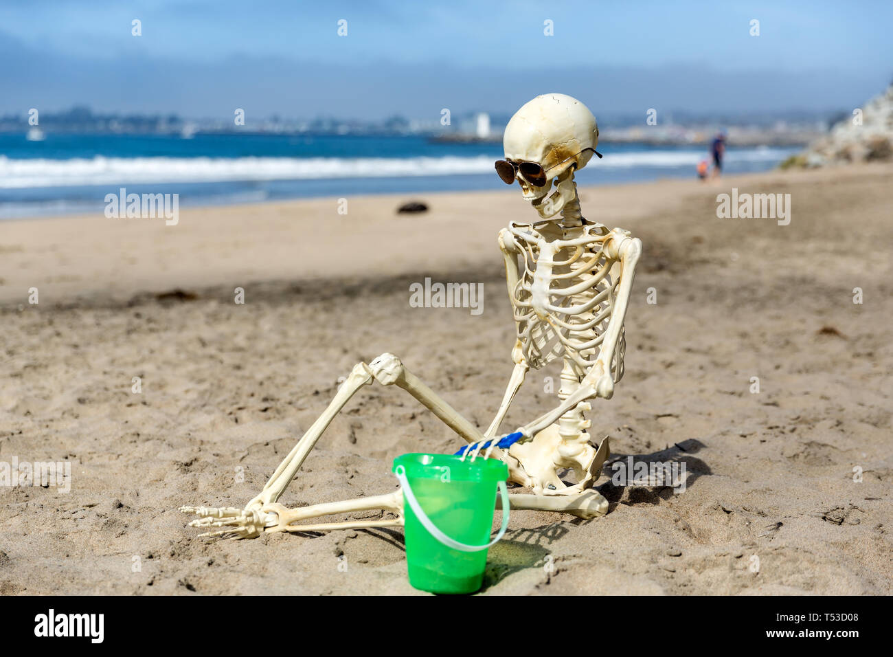 Skeleton sits on the beach playing in the sand with a bucket and shovel  Stock Photo - Alamy