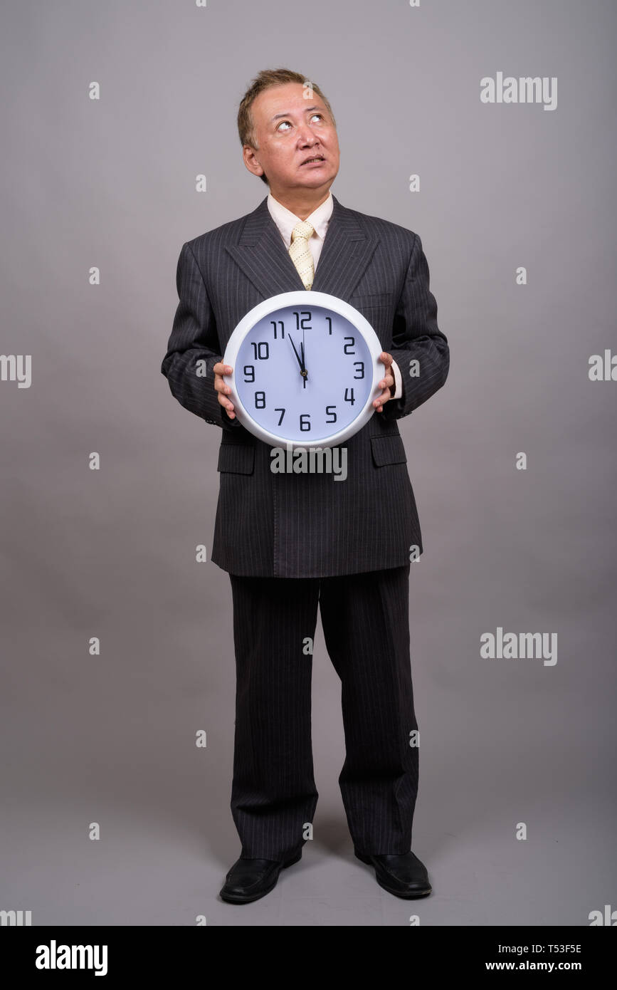 Portrait of mature Asian businessman against gray background Stock Photo