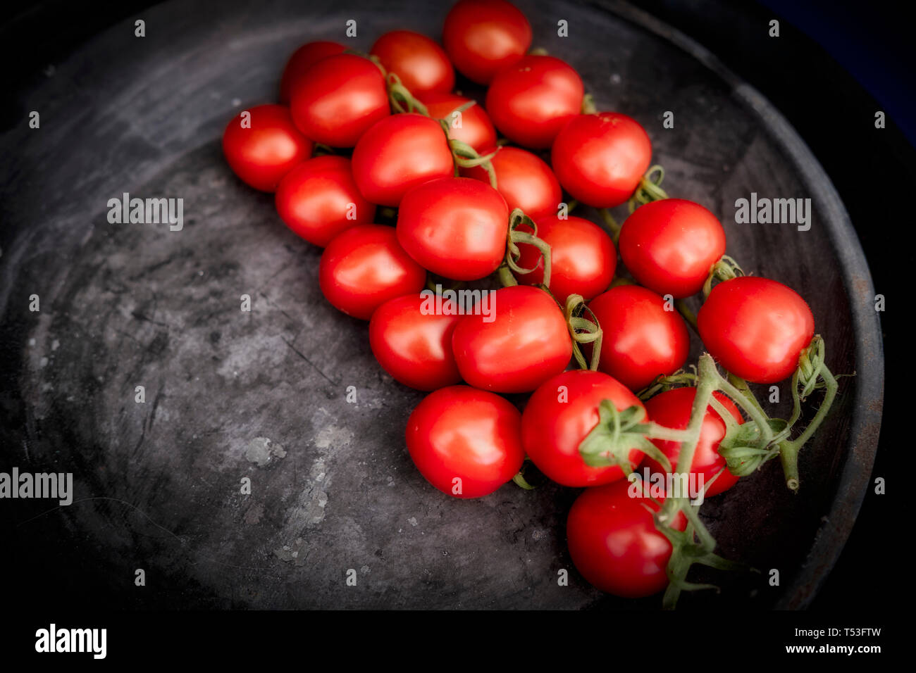 A cluster of red Cherry Tomatoes on a black tray Stock Photo - Alamy