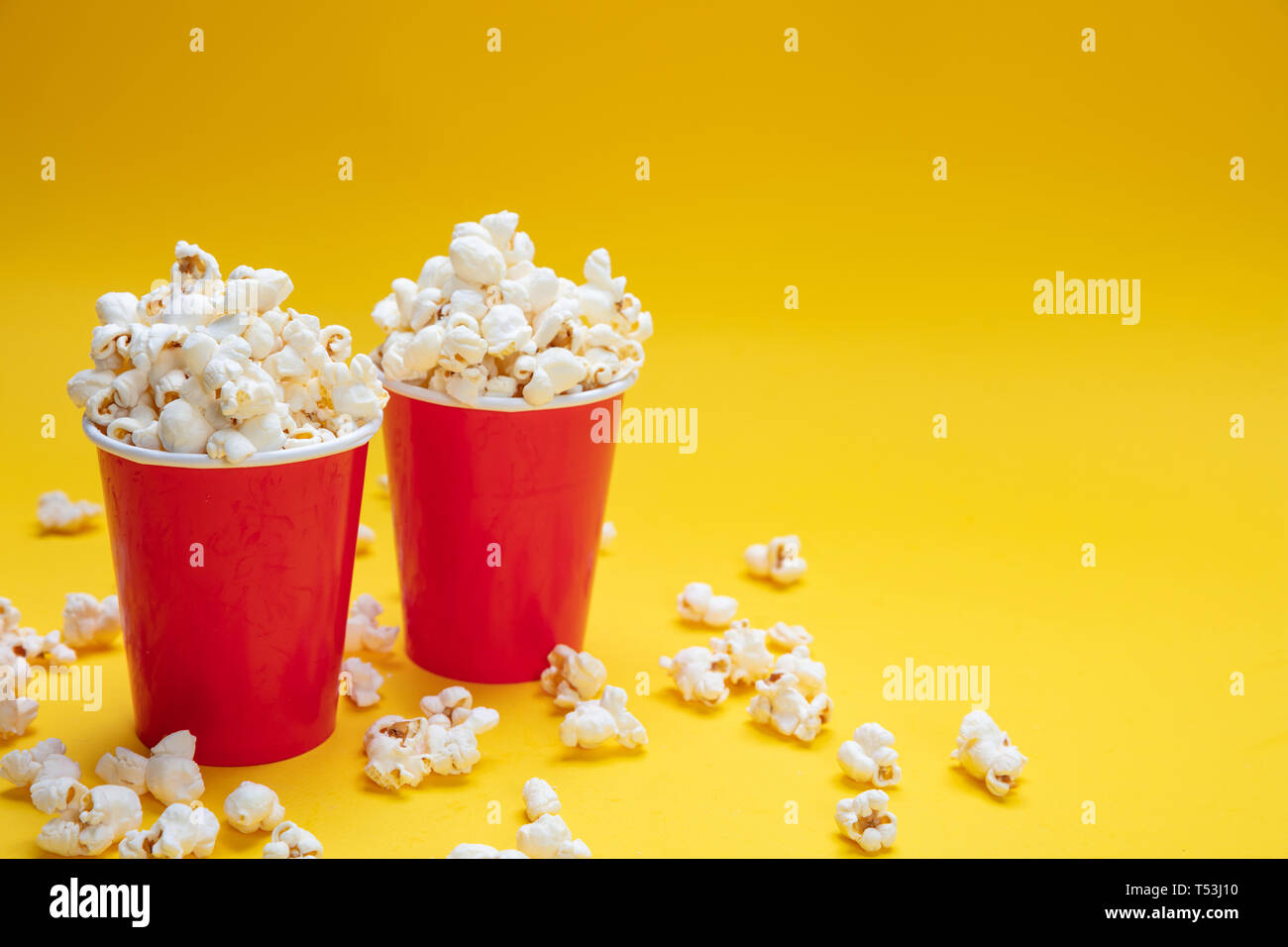 Fresh salty pop corn in two red carton containers, yellow color background, copy space Stock Photo