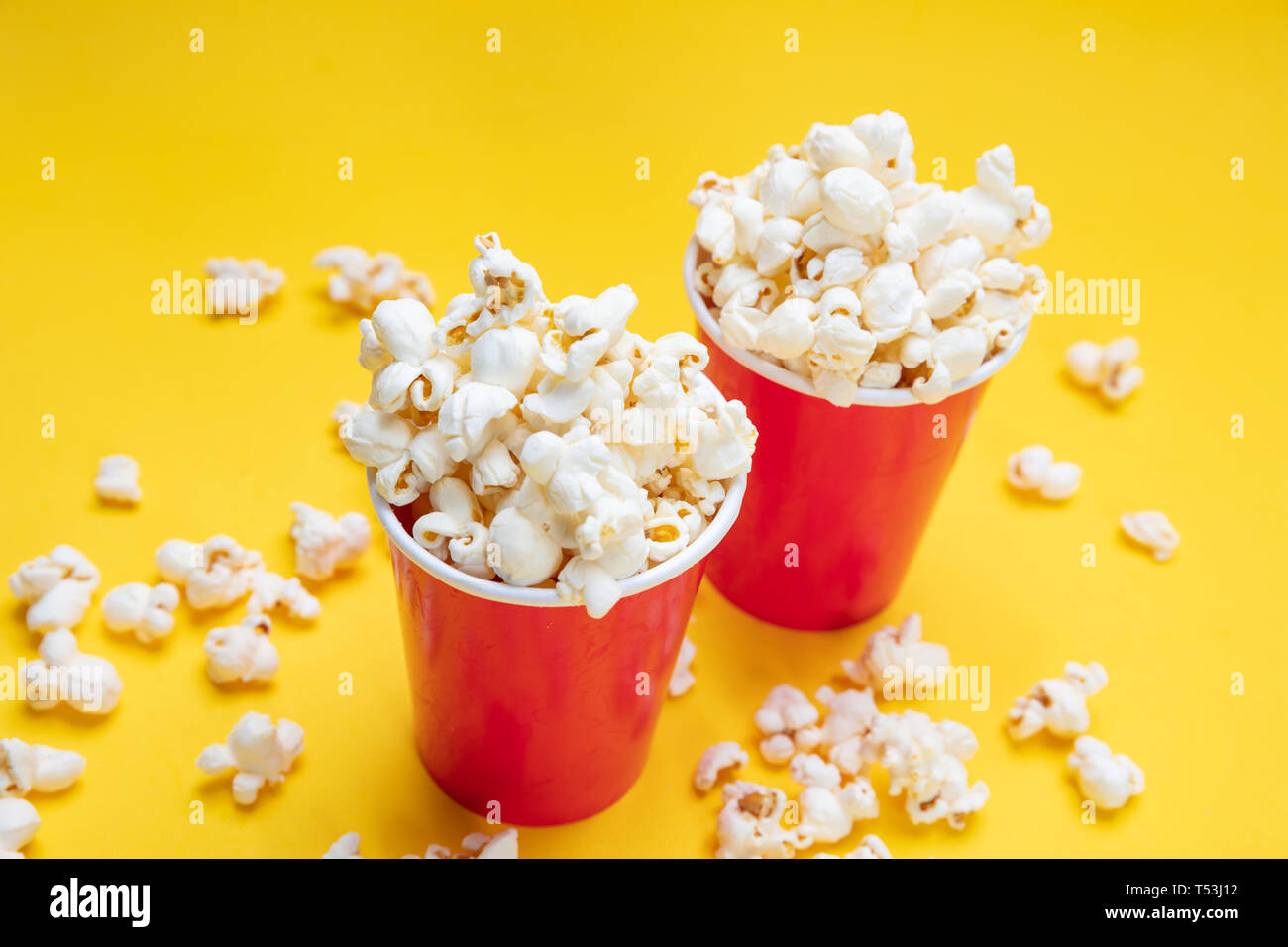 Fresh salty pop corn in two red carton containers, yellow color background, closeup view Stock Photo