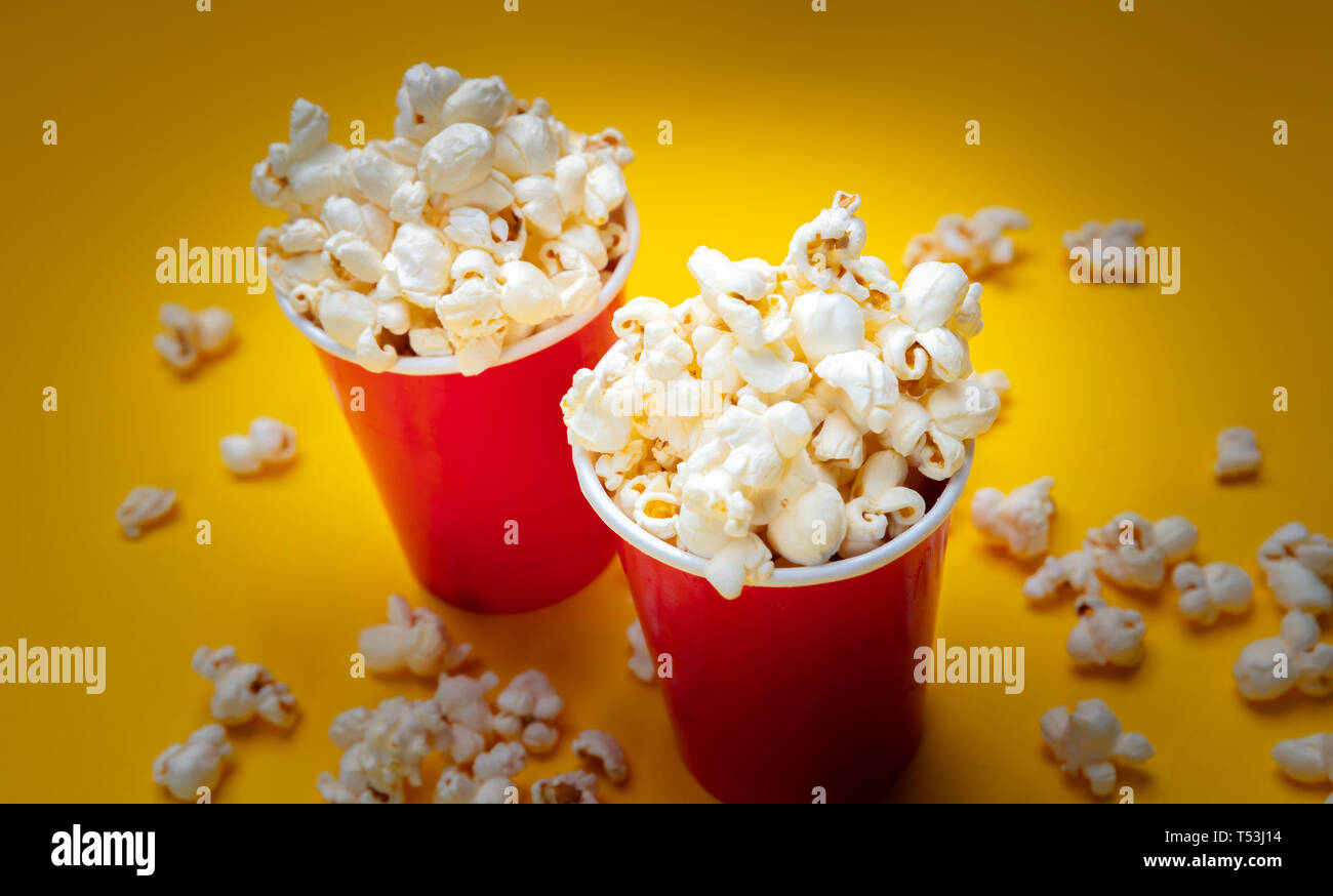 Fresh salty pop corn in two red carton containers, yellow color background, closeup view Stock Photo