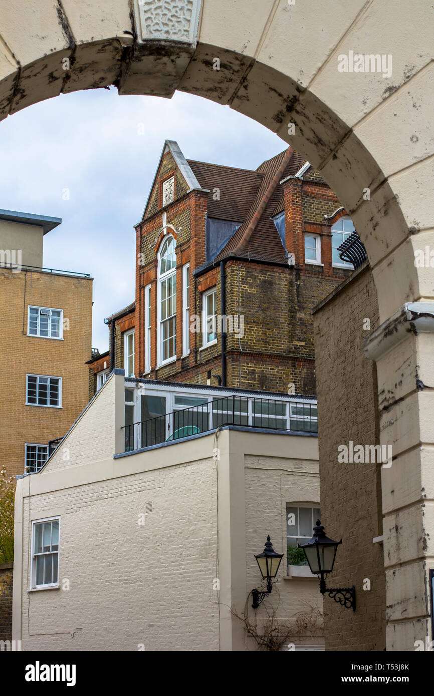 Brick multi-level house with large beautiful windows. Picture taken through the old arch. Central London. Stock Photo