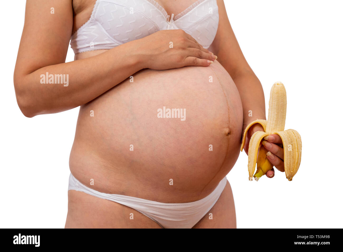 Pregnant woman holding banana at her tummy. Bananas are a great source of vitamin B6 which helps with morning sickness as it has fibre, vitamin C and  Stock Photo