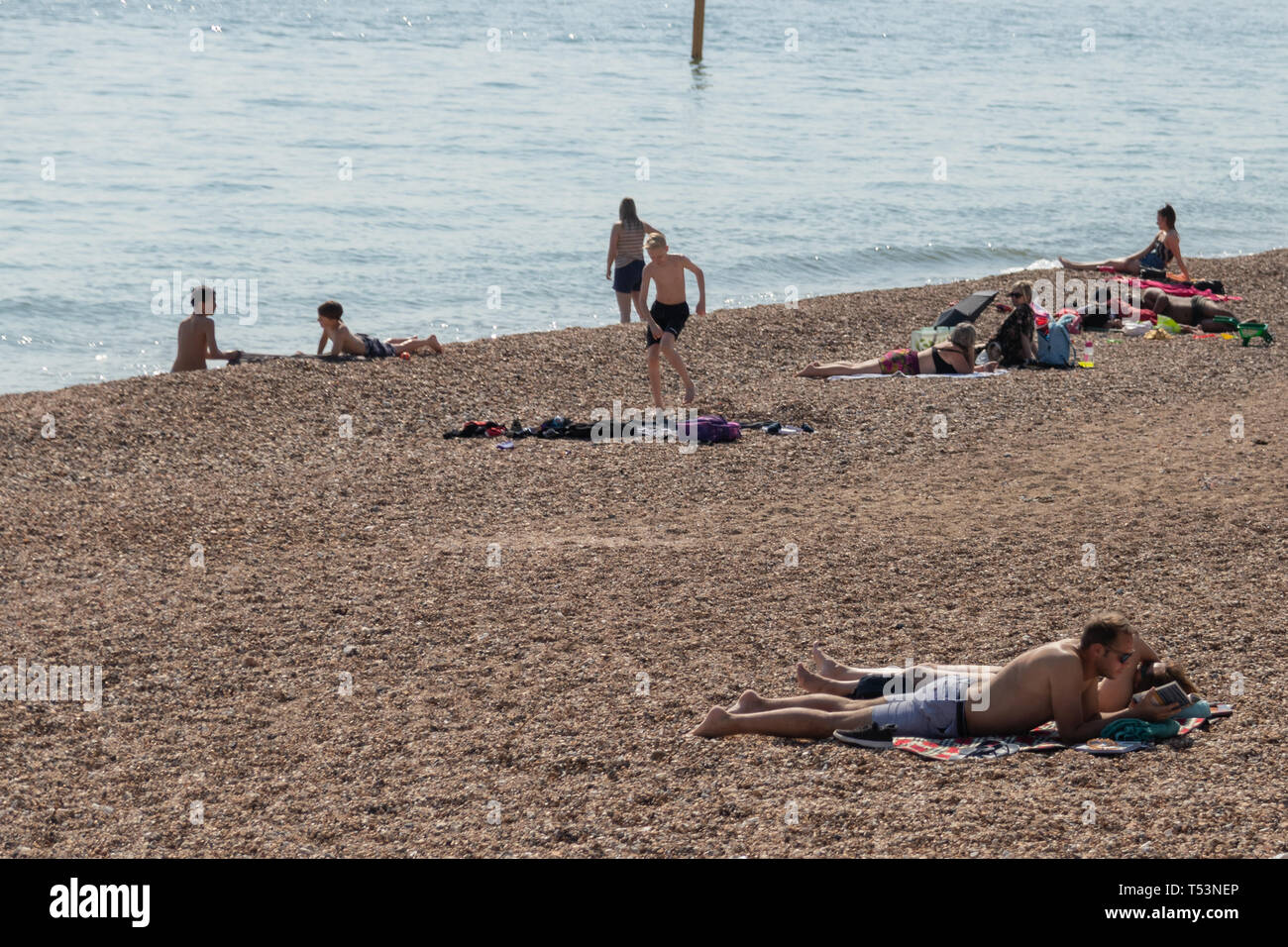Crowds enjoying the sunshine on a pebble beach in the UK Stock Photo