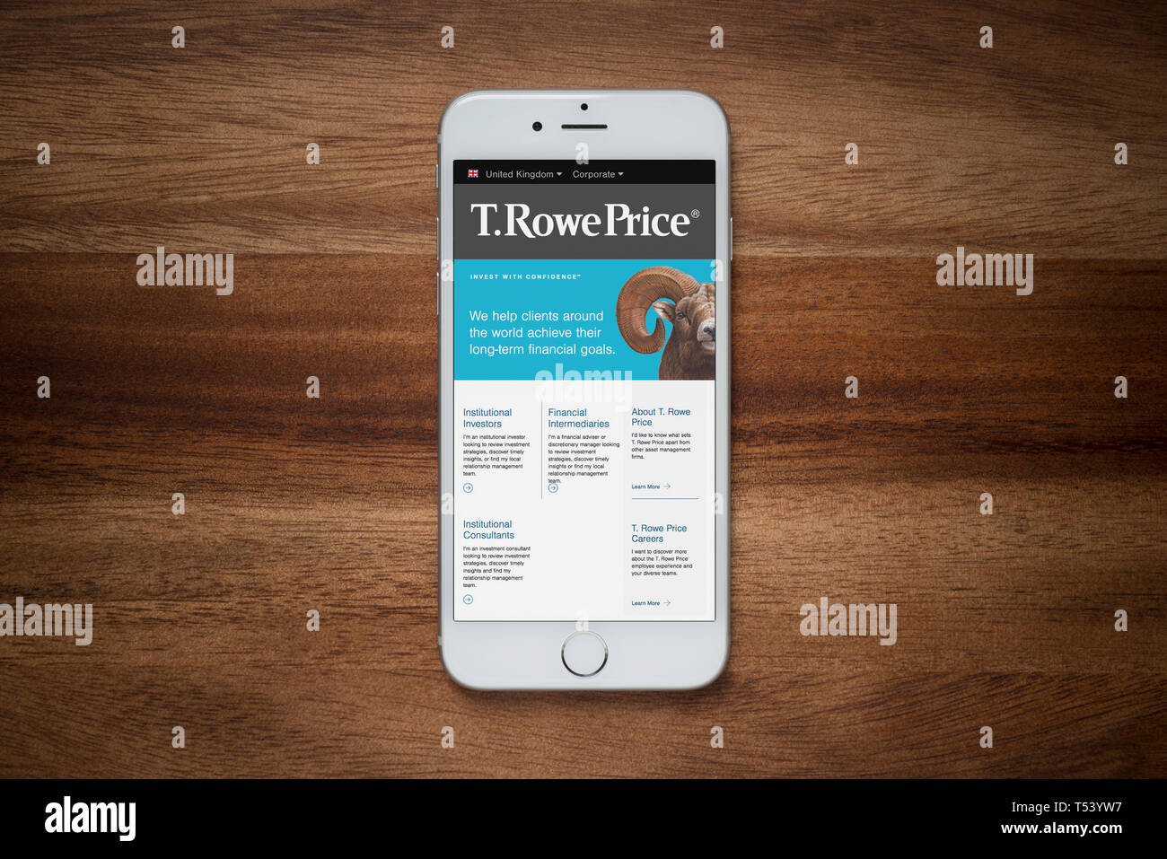 An iPhone showing the T. Rowe Price website rests on a plain wooden table (Editorial use only). Stock Photo